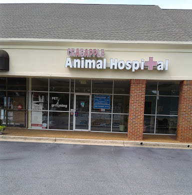 Exterior of Crabapple Animal Hospital with glass doors and windows, featuring signs for pet grooming services.